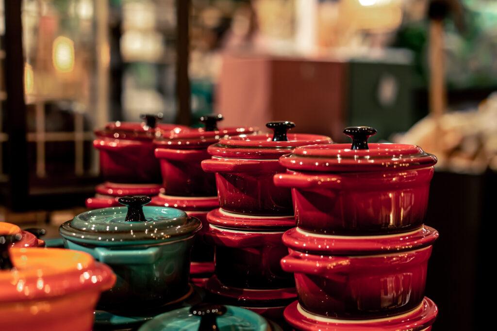 Vintage Kitchenware Brands - Small Dutch ovens in a shop window, miniature crockery on a blurry background.