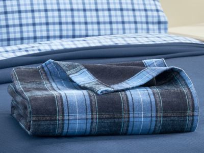Blue plaid woven cotton throw blanket folded on a farmhouse bed