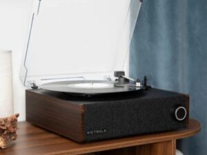 Premium vintage-style record player with walnut finish and clear dust cover on a wooden cabinet.