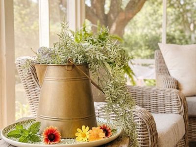 Decorative gold garden pitcher vase filled with greenery and flowers