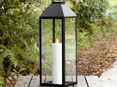Tall black classic lantern with candle displayed outdoors