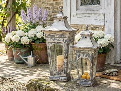 Windsor cottage candle lanterns displayed among flowers outdoors
