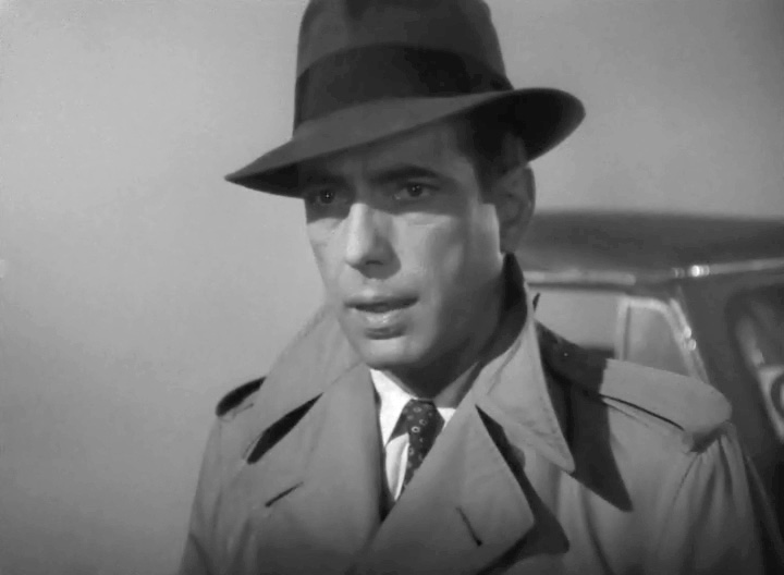 Humphrey Bogart wearing a classic fedora and trench coat in the 1942 film Casablanca, illustrating vintage men's hats in Hollywood.
