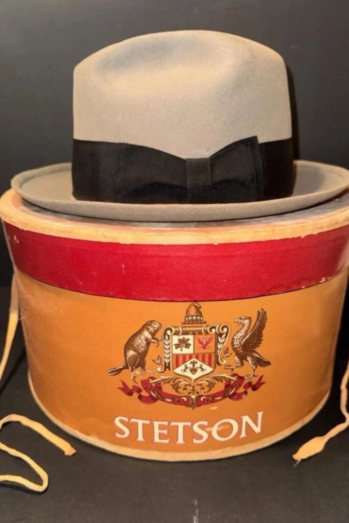 Collection of vintage fedoras and a Panama hat displayed with an antique hatbox